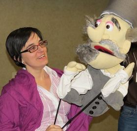 Tania looking at a large puppet she is holding